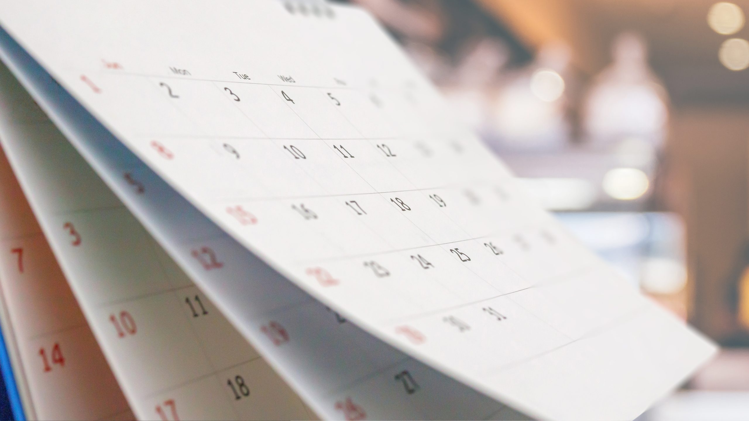 <p>Close up white paper desk calendar with blurred bokeh background appointment and business meeting concept</p>
