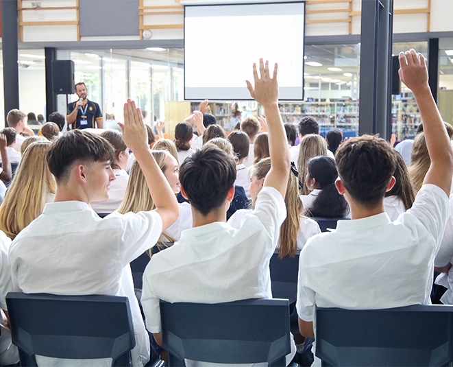 A group or students with their hands up during a presentation