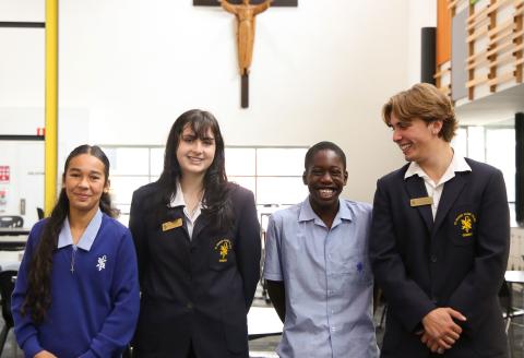 Four students standing together smiling