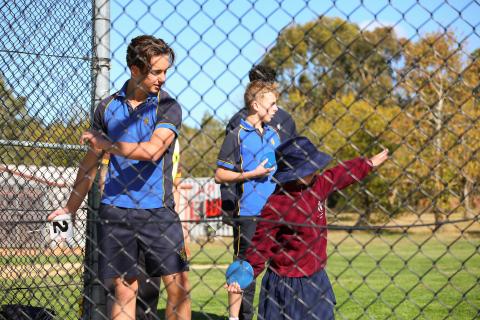 A male student guiding a younger female student on disc throwing